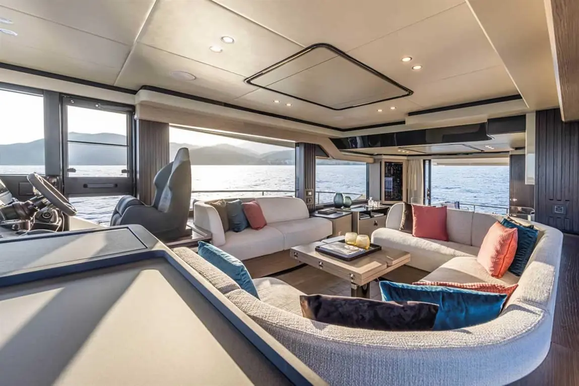 Luxurious yacht interior featuring a spacious lounge with modern furnishings, a table, and panoramic views of the water.